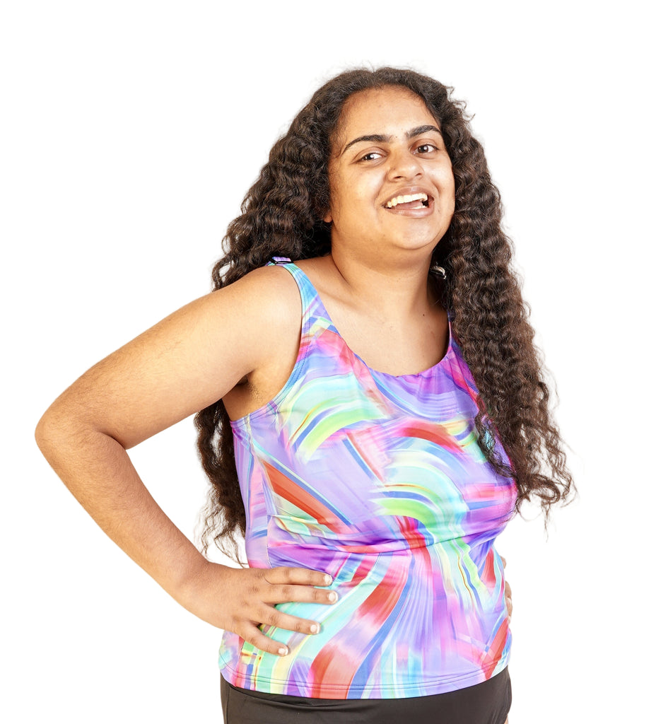 A woman wearing a multicolored floral tankini top with adjustable spaghetti straps, posing against a white background.
